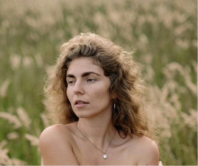 Donna con capelli ricci e voluminosi in un campo, immagine di copertina articolo sulla perdita di capelli in menopausa